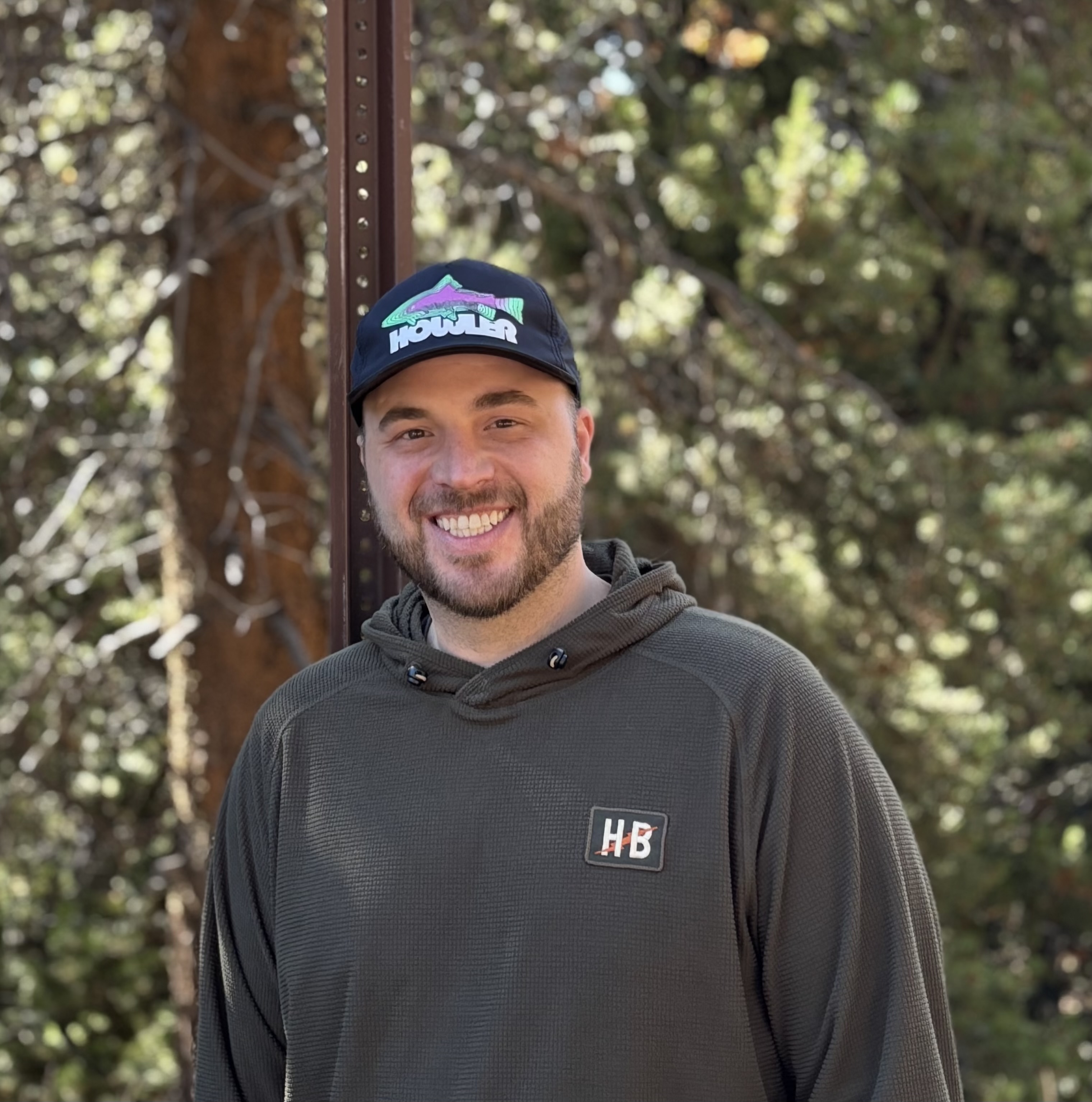 Zack smiling outdoors wearing a Howler Brothers hat